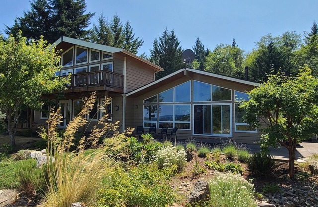 Modern retreat with serene canal, forest, and mountain views.