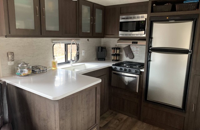 Modern RV camper with all the perks Nestled in tree at lake edge