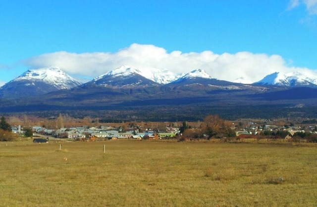 "Small house on a raised hill, facing the imposing Andes mountain range."