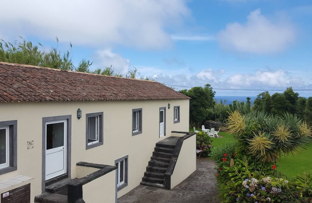Einfaches Landhaus mit Frühstücksterrasse im sonnigen Garten, Meerblick
