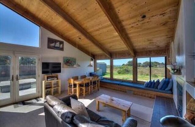 Wide open meadow view with ocean peeks through the trees.